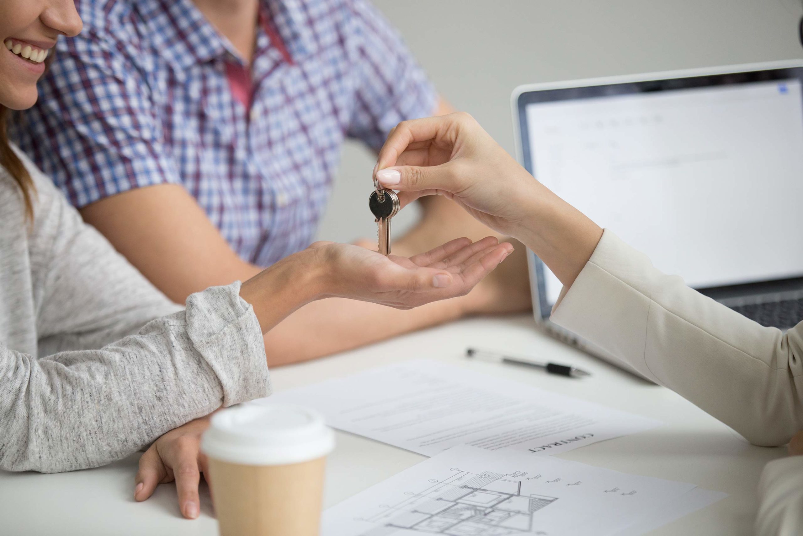 Buying a new house concept: realtor giving keys to couple - closeup